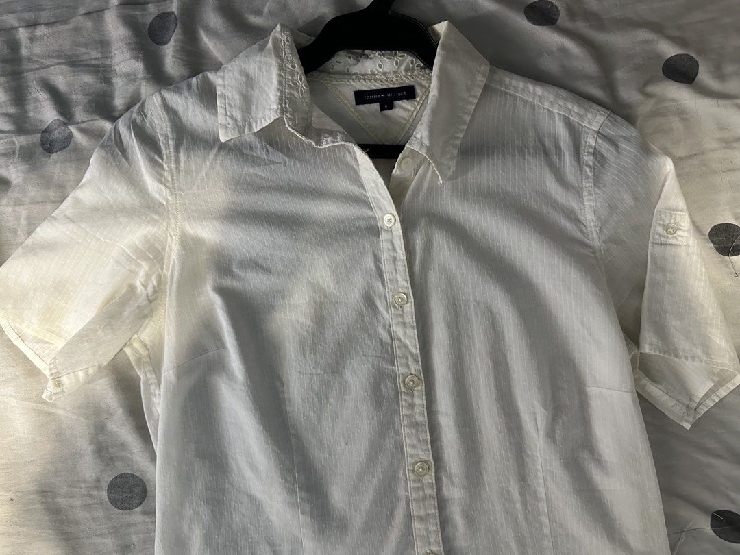 Tommy Hilfiger Short Sleeve White Button Down Shirt (Category: Shirts) located in Davao. Submitted by sniks_. (Listing ID 1468085739, Image 1). Description: - Brand: Tommy Hilfiger - Color: Classic White - Size: 6 (Tailored fit with front princess seams) - Details: Subtle vertical stripe texture and delicate eyelet lace along the inner neckline - Sleeves: Roll-tab short sleeves - Closure: Front button placket with matching white buttons - Conditi