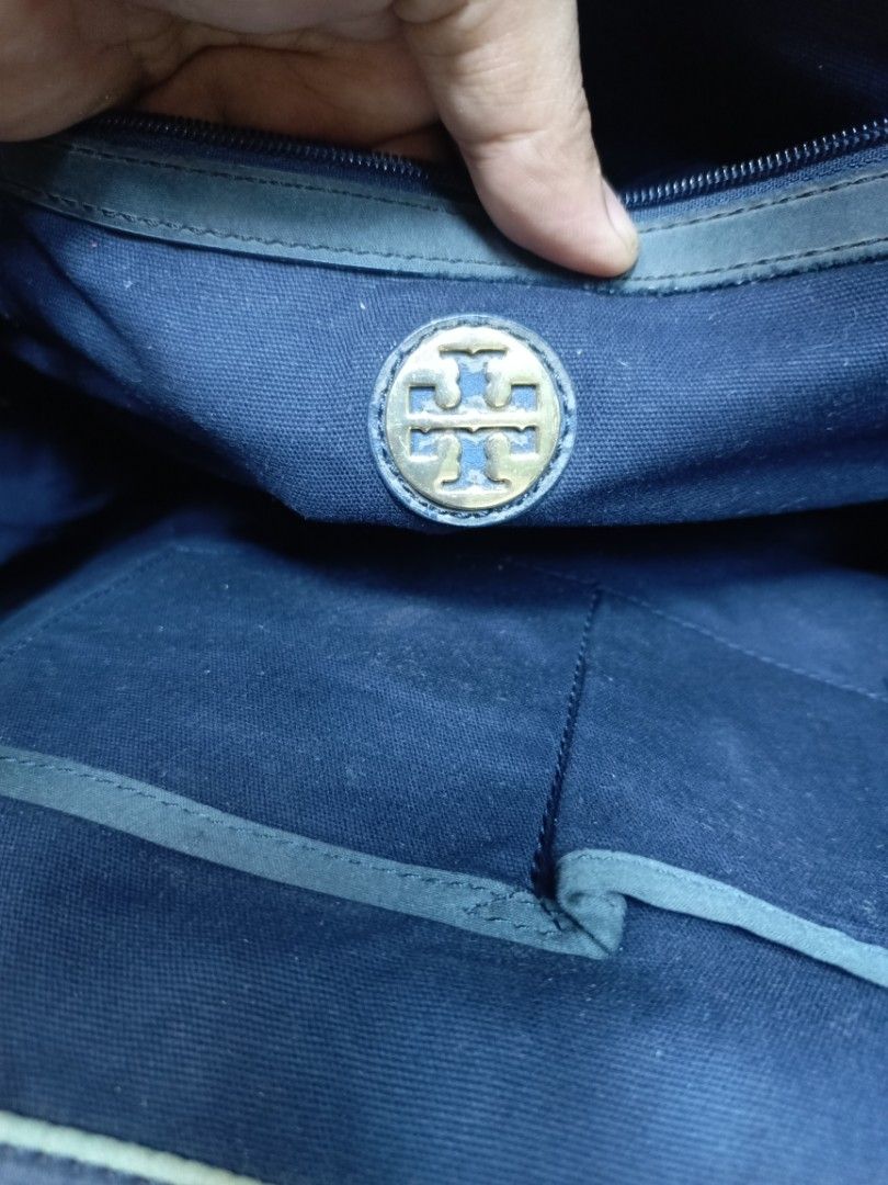 Tory Burch Striped Canvas Tote Bag (Category: Tote Bags) located in Manila. Submitted by del_thrifts03 (Listing ID 1468112220, Image 3). Description: - Brand: Tory Burch - Design: Blue, white, and green stripes with large front debossed logo - Material: Sturdy canvas body with durable leather handles and corner patches - Hardware: Gold-tone hardware with branded zipper pull - Closure: Secure top magnetic snap - Interior: Navy blue fabric lining w