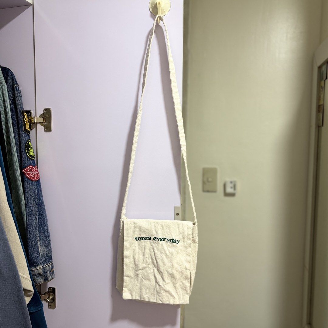 totes everyday canvas crossbody bag (Category: Cross-body Bags) located in Cavite. Submitted by lovedbysham (Listing ID 1468275874, Image 1). Description: - Color: Off-white canvas - Design: Green embroidered 'totes everyday' lettering on the front flap - Storage: Multiple inside front pockets under the flap - Strap: Long shoulder strap attached at the sides - Style: Simple, casual, and perfect for daily use.