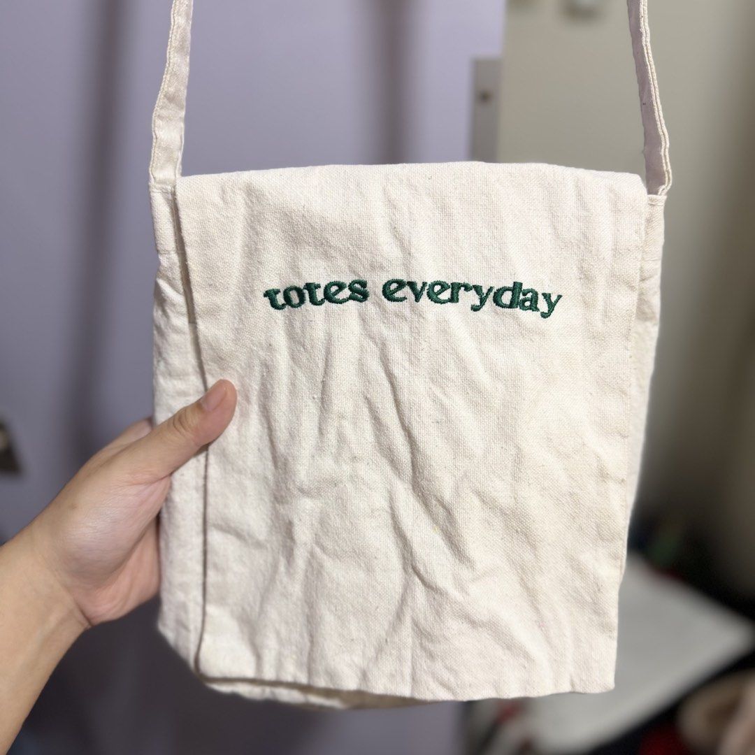totes everyday canvas crossbody bag (Category: Cross-body Bags) located in Cavite. Submitted by lovedbysham (Listing ID 1468275874, Image 2). Description: - Color: Off-white canvas - Design: Green embroidered 'totes everyday' lettering on the front flap - Storage: Multiple inside front pockets under the flap - Strap: Long shoulder strap attached at the sides - Style: Simple, casual, and perfect for daily use.
