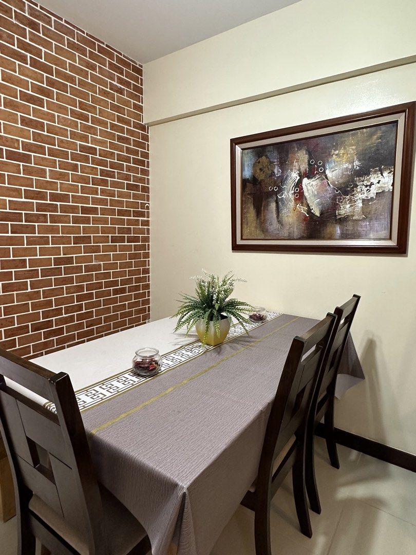Verawood Residences 2 br unit (Category: Apartments & Condos) located in Taguig. Submitted by indieboy13 (Listing ID 1468267274, Image 3). Description: Complete furniture setup for the living room. Brown L-shaped sectional sofa with soft cushions. Wooden coffee table featuring a lower shelf for storage. Light wood TV console with open shelving and cabinet space. Includes a large flat screen television, decorative wall art panels, area rug, tall f