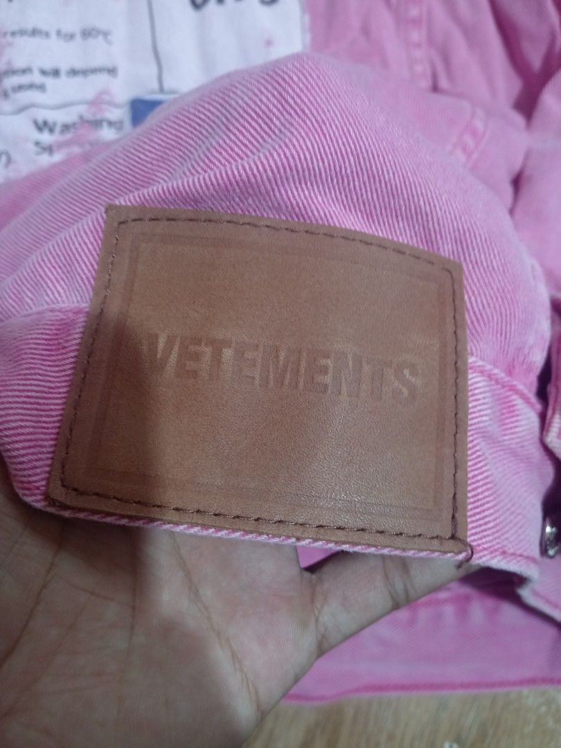 VETEMENTS Pink Denim Jacket Size L (Category: Coats, Jackets and Outerwear) located in Baguio. Submitted by solo_ukay (Listing ID 1468257137, Image 3). Description: - Brand/Model: VETEMENTS pink denim jacket - Size: L - Material: 100% cotton, Made in China - Design Details: Bold black lettering on chest, large energy label graphic patch on back, and brown leather patch near bottom hem - Features: Full button-up front with metal hardware and multi
