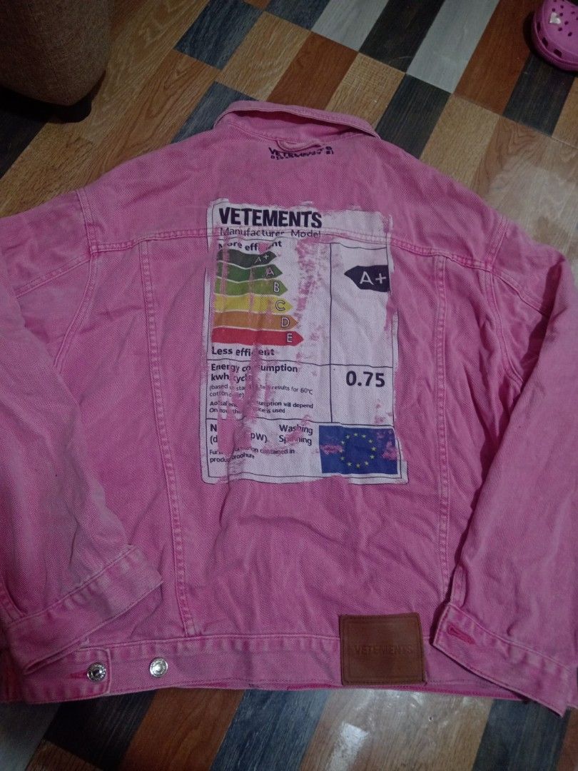VETEMENTS Pink Denim Jacket Size L (Category: Coats, Jackets and Outerwear) located in Baguio. Submitted by solo_ukay (Listing ID 1468257137, Image 2). Description: - Brand/Model: VETEMENTS pink denim jacket - Size: L - Material: 100% cotton, Made in China - Design Details: Bold black lettering on chest, large energy label graphic patch on back, and brown leather patch near bottom hem - Features: Full button-up front with metal hardware and multi