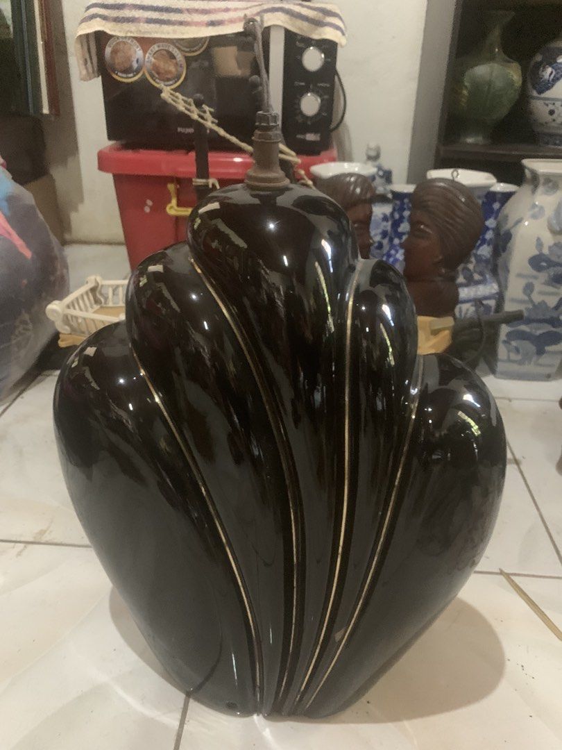 Vintage Black Ceramic Art Deco Lamp Base (Category: Lighting) located in Quezon City. Submitted by sojisup (Listing ID 1468142238, Image 1). Description: - Style: Vintage Art Deco black ceramic lamp base with elegant curved shell design - Details: Glossy finish with striking gold trim lines along the ridges - Build: Heavy and stable base featuring a metal harp fixture and threaded rod - Condition: Good vintage condition with some oxidation on met