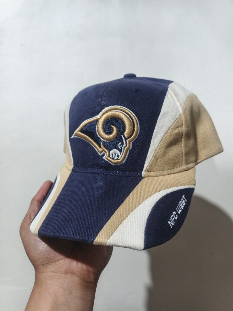 Vintage St. Louis Rams Reebok NFL Cap Hat (Category: Caps & Hats) located in San Jose. Submitted by ezsenthrift475 (Listing ID 1468233664, Image 1). Description: - Vintage St. Louis Rams cap by Reebok - Classic blue, gold, and white colorblock design - Embroidered team logo on the front - 'NFC West' text embroidered on the brim - Adjustable strapback closure with 'ST. LOUIS RAMS' detail - Official NFL interior tag.
