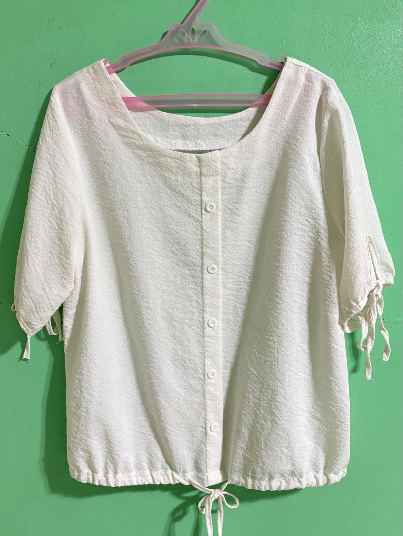 White Women’s Blouse Top (Category: Blouses) located in Bulacan. Submitted by franchesca_vg (Listing ID 1468169672, Image 2). Description: - Color: White - Size: Large ~ xl - Style: Short-sleeve blouse with scoop neckline - Details: Front button closure, cute ties on sleeves, and adjustable drawstring hem - Fabric: Thin material — best worn with an inner/camisole - never worn! Kindly DM me for more info & pics 💌.