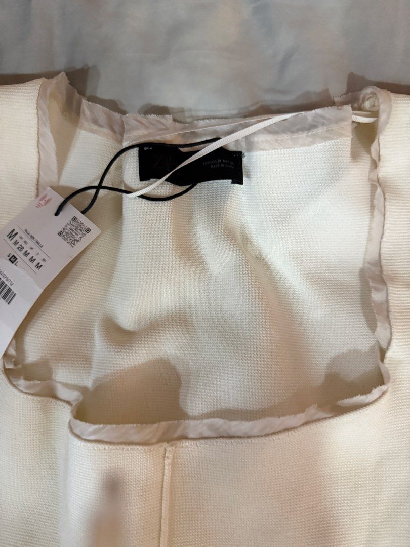 Zara Square Neck Knit Top White Size M (Category: Sleeveless) located in Pasig City. Submitted by atbp__ (Listing ID 1468111049, Image 2). Description: - Brand: Zara - Style: Knit top with square neckline and short cap sleeves - Color: Off-white - Size: Medium (M) - Condition: Brand new with original store tag attached - Details: Textured knit fabric with delicate trim along the collar, sleeves, and hem - Reason for selling: Wardrobe clearance.