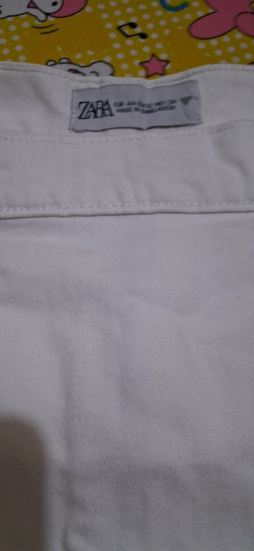 ZARA White Denim Skirt Size 38 (Category: Skirts) located in Manila. Submitted by katkween23 (Listing ID 1468079963, Image 3). Description: - Brand: ZARA - Style: White denim skirt with asymmetrical button front - Size: 38 on tag - Measurements: Waist approx. 16-17" across, Length approx. 16" - Features: Sturdy denim fabric, functional front pockets - Condition: Good, with a small faint stain near the right pocket area - Versatile, classic piece 