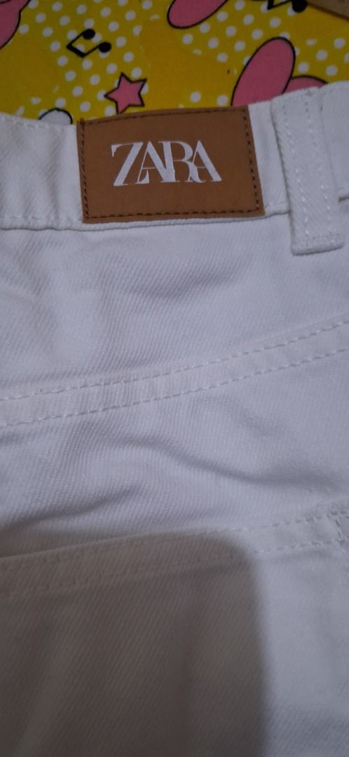 ZARA White Denim Skirt Size 38 (Category: Skirts) located in Manila. Submitted by katkween23 (Listing ID 1468079963, Image 2). Description: - Brand: ZARA - Style: White denim skirt with asymmetrical button front - Size: 38 on tag - Measurements: Waist approx. 16-17" across, Length approx. 16" - Features: Sturdy denim fabric, functional front pockets - Condition: Good, with a small faint stain near the right pocket area - Versatile, classic piece 