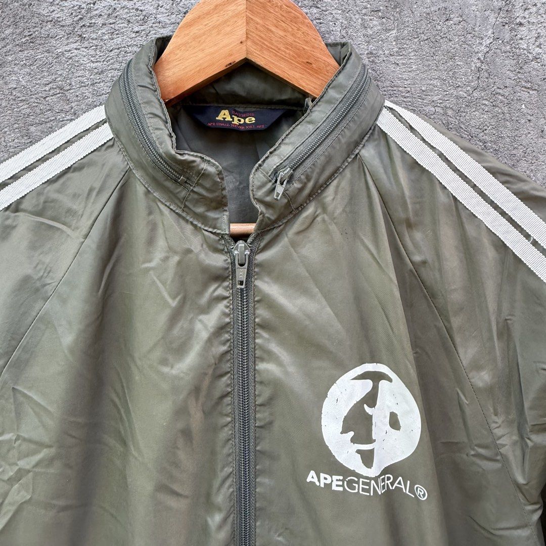 A Bathing Ape Ape General Track Jacket Olive (Category: Coats, Jackets and Outerwear) located in Caloocan City. Submitted by ayogorenia1002 (Listing ID 1468351398, Image 2). Description: - Brand: A Bathing Ape (BAPE) - Color: Olive green with white double sleeve stripes - Details: Full zip, high collar with unique zipper accent, Ape General chest logo - Pockets: Two zippered side pockets - Condition: Excellent / Pre-owned - Shipping: Fast ship na