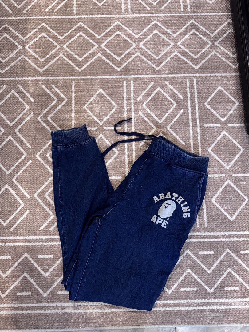 A Bathing Ape BAPE Navy Sweatpants Joggers Size M (Category: Joggers) located in Bulacan. Submitted by zyannechlo86360 (Listing ID 1468342683, Image 1). Description: - Brand: BAPE - Color: Navy blue (washed denim look with seam fading) - Size: Medium (tag attached inside waistband) - Features: Drawstring waist, ribbed cuffs, and iconic ape head logo with text near the front pocket - Authenticity: Includes gold ape tag on inner wash label 28-32 wa