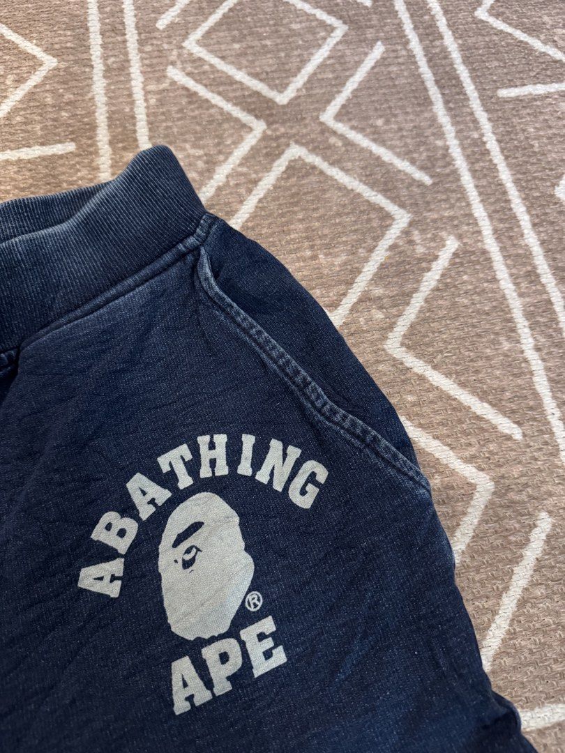 A Bathing Ape BAPE Navy Sweatpants Joggers Size M (Category: Joggers) located in Bulacan. Submitted by zyannechlo86360 (Listing ID 1468342683, Image 2). Description: - Brand: BAPE - Color: Navy blue (washed denim look with seam fading) - Size: Medium (tag attached inside waistband) - Features: Drawstring waist, ribbed cuffs, and iconic ape head logo with text near the front pocket - Authenticity: Includes gold ape tag on inner wash label 28-32 wa