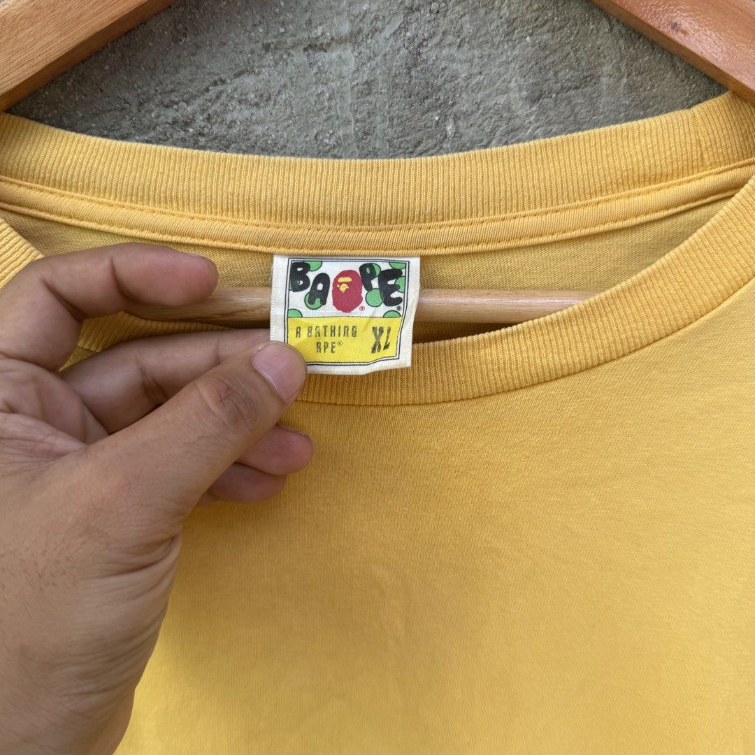 A Bathing Ape Shark Yellow Tee XL (Category: Tshirts & Polo Shirts ) located in Caloocan City. Submitted by ayogorenia1002 (Listing ID 1468350615, Image 2). Description: - Brand: A Bathing Ape (BAPE) - Color: Bright Yellow - Size: Men's XL - Design: Colorful shark jaw and eye graphics near bottom sides - Details: Signature ape head patch on sleeve, classic collar tags intact - Condition: Solid streetwear piece, well-maintained - Shipping or meet-