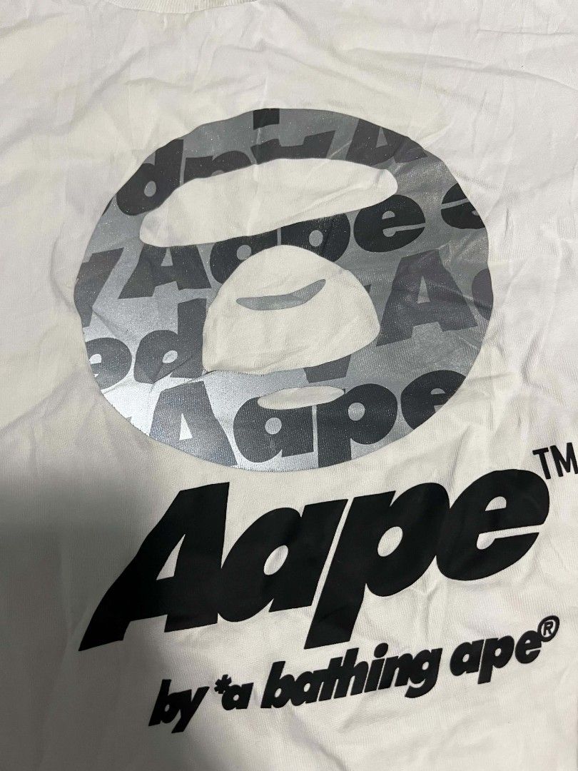 Aape By A Bathing Ape T-Shirt White Large (Category: Tshirts & Polo Shirts ) located in Compostela. Submitted by zackthrift07 (Listing ID 1468347948, Image 2). Description: - Brand: Aape by A Bathing Ape - Color: White with silver grey and black graphic - Size: Large - Material: 100% premium cotton - Design: Big Ape head logo on chest, signature repeating Aape inner tape, crew neck, short sleeves - Origin: Made in China - Condition: Brand new / E