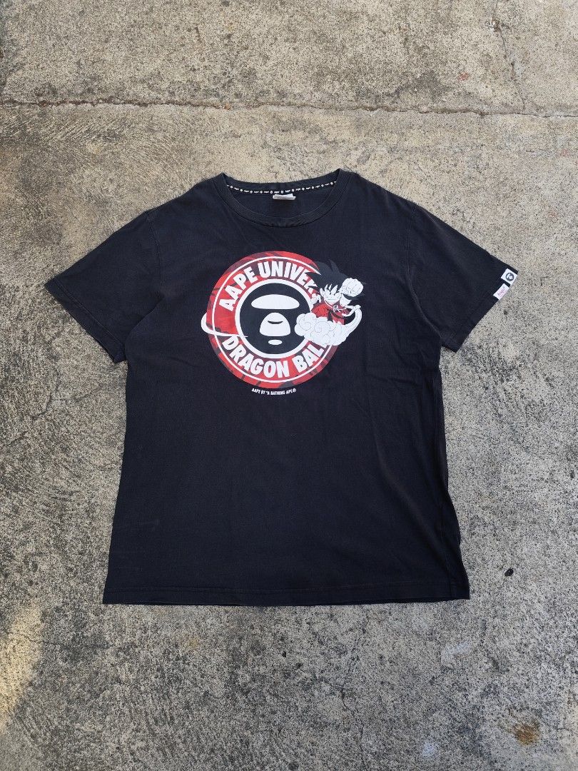 AAPE X DRAGON BALL (Category: Tshirts & Polo Shirts ) located in Lemery. Submitted by dailythriftin (Listing ID 1468433863, Image 1). Description: AAPE Universe Dragon Ball graphic printed across the front in red and white. Black colorway, short sleeves with sleeve tag. AAPE branded interior neck taping and collar tag reading XL. Regular fit casual tee featuring Goku riding the Flying Nimbus. Aape Size: Large Dimes: 21x28 Excellent condition Issu