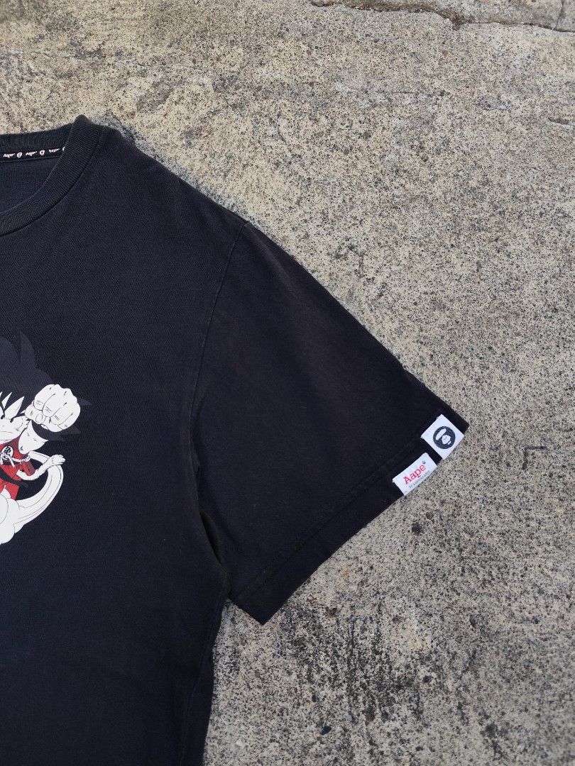 AAPE X DRAGON BALL (Category: Tshirts & Polo Shirts ) located in Lemery. Submitted by dailythriftin (Listing ID 1468433863, Image 2). Description: AAPE Universe Dragon Ball graphic printed across the front in red and white. Black colorway, short sleeves with sleeve tag. AAPE branded interior neck taping and collar tag reading XL. Regular fit casual tee featuring Goku riding the Flying Nimbus. Aape Size: Large Dimes: 21x28 Excellent condition Issu