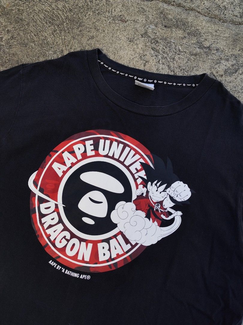 AAPE X DRAGON BALL (Category: Tshirts & Polo Shirts ) located in Lemery. Submitted by dailythriftin (Listing ID 1468433863, Image 3). Description: AAPE Universe Dragon Ball graphic printed across the front in red and white. Black colorway, short sleeves with sleeve tag. AAPE branded interior neck taping and collar tag reading XL. Regular fit casual tee featuring Goku riding the Flying Nimbus. Aape Size: Large Dimes: 21x28 Excellent condition Issu