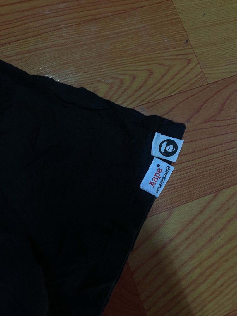 Aape x Garfield Black T-Shirt (Category: Tshirts & Polo Shirts ) located in Ozamiz City. Submitted by tripft.vonde (Listing ID 1468312263, Image 3). Description: Black short sleeve t-shirt from the Aape by A Bathing Ape and Garfield collaboration. Small Garfield and Aape branding on the left chest. Larger graffiti-style graphic on the back with camouflage fill. Small woven logo tags on the left sleeve hem. Collar tape features repeated Aape text.