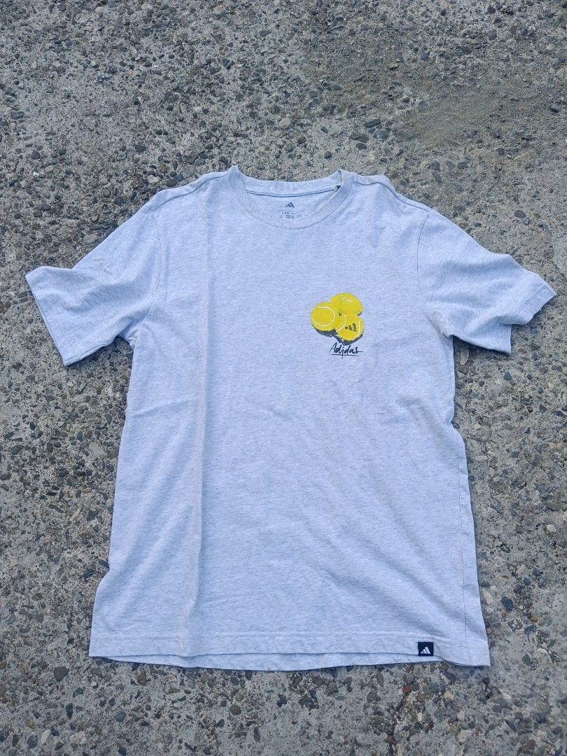 Adidas Grey Tennis Ball Graphic T-Shirt (Category: Tshirts & Polo Shirts ) located in Urdaneta. Submitted by tetsudoubletaps (Listing ID 1468497708, Image 1). Description: + SF 22 x 27 - 28 with minimal stains sa neck and shoulder, hindi naman masyadong visible pwede pa sigurong maalis pag nilabhan - Brand: Adidas - Color: Grey with yellow tennis ball graphic on left chest - Size/Fit: Regular fit, short sleeves - Material: 100% cotton, Made in Pa