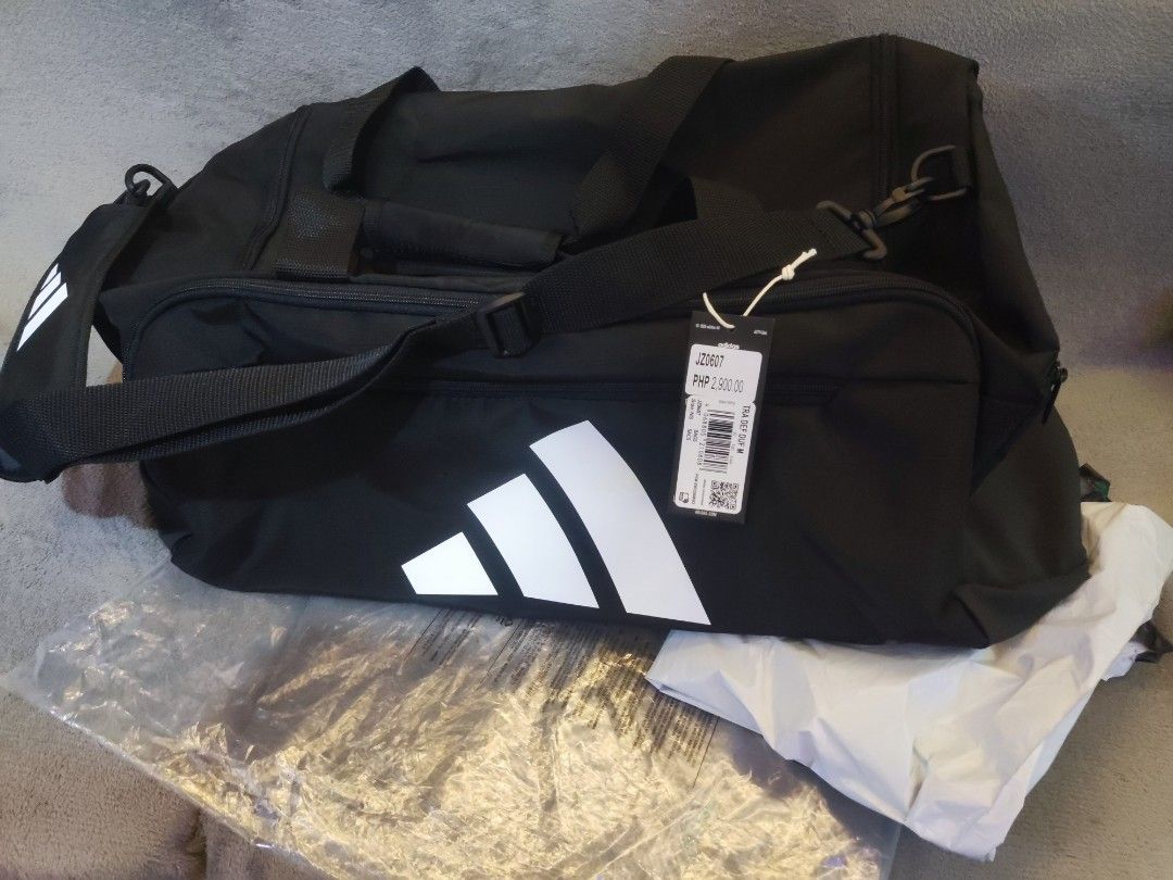 Adidas Training Duffel Bag Medium Black (Category: Sling Bags) located in Navotas City. Submitted by jhurram002 (Listing ID 1468405935, Image 2). Description: - Brand: Adidas - Color: Black with large white logo on the front - Size: Medium training duffel bag - Condition: Brand new with original store tags attached - Features: Sturdy shoulder strap with heavy-duty plastic clip and durable zippers for main compartment and side pocket srp: 2,900 no
