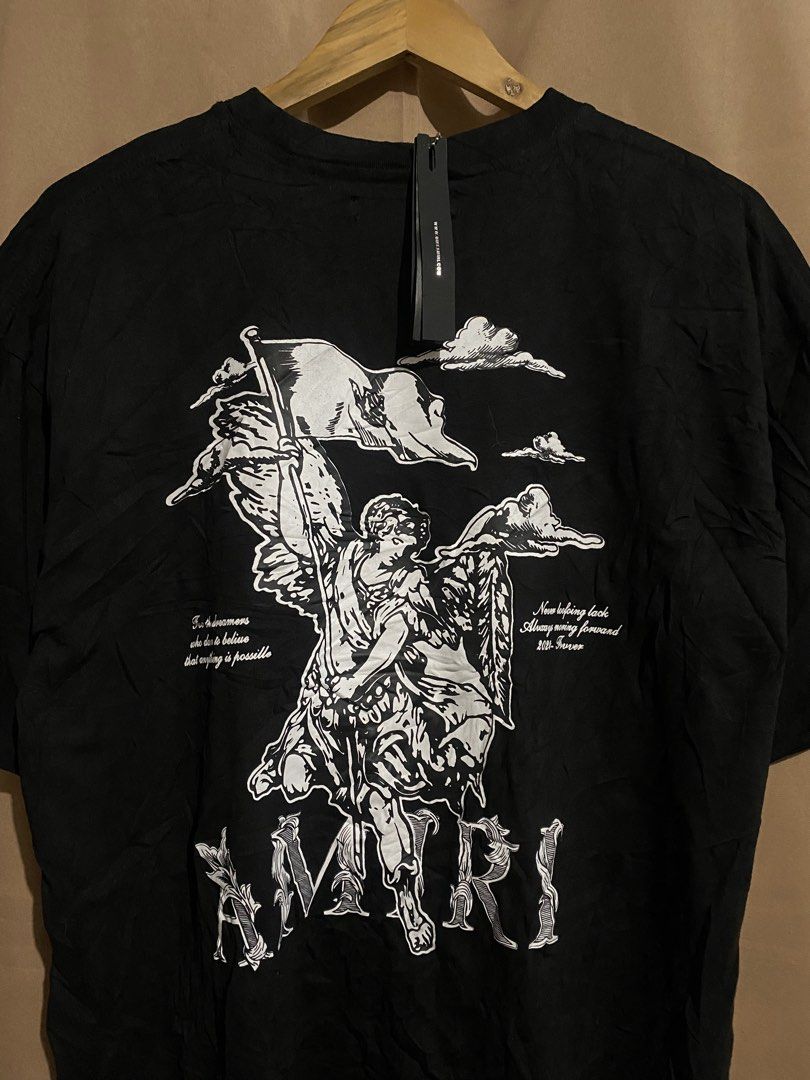 AMIRI Black Angel Flag Print Tee (Category: Tshirts & Polo Shirts ) located in Manila. Submitted by why_notph (Listing ID 1468422678, Image 2). Description: - Brand: Amiri - Color: Classic Black - Design: Large angel with flag graphic, cloud details, and bold Amiri branding on the back - Inclusions: Original neck label and hanging hangtag with ball chain - Condition: Brand new with tags - Meet-ups or shipping available nationwide via J&T/Flash - 