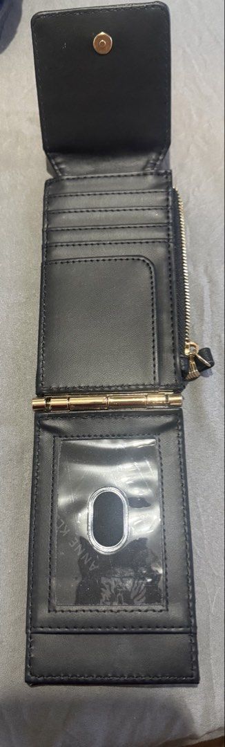 Anne Klein Black Folding Wallet with Card Slots (Category: Wallets & Card holders) located in Cainta. Submitted by mykee1 (Listing ID 1468370357, Image 1). Description: All must go! From US - Brand: Anne Klein - Material: Black faux leather with gold-tone hardware - Design: Tri-fold with secure snap button closure - Features: Multiple card slots, clear ID window with visible branding, and side zipper coin pocket - Size: Compact, fits easily in sm