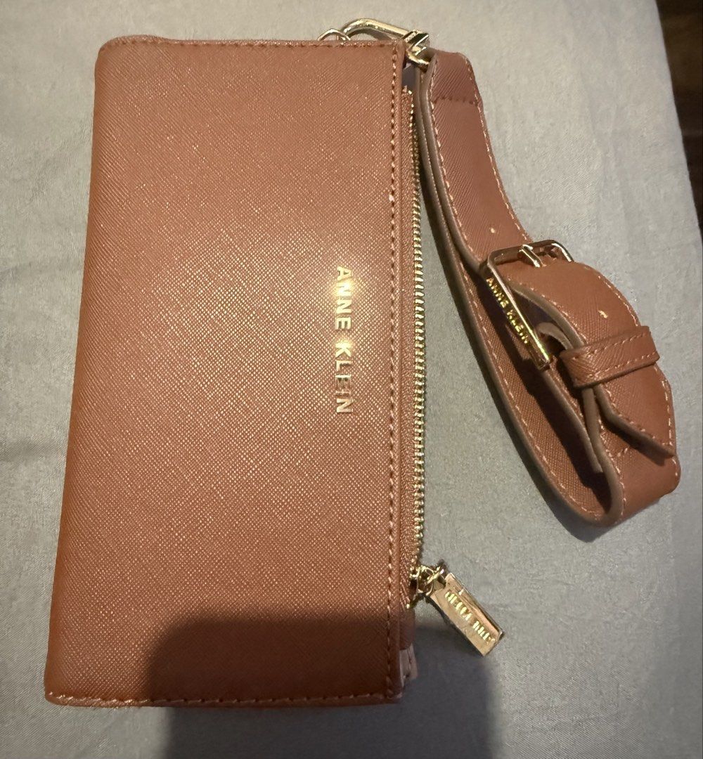 Anne Klein Brown Wristlet Wallet (Category: Wallets & Card holders) located in Cainta. Submitted by mykee1 (Listing ID 1468372578, Image 1). Description: - Brand: Anne Klein - Material: Premium brown textured faux leather with elegant gold hardware - Closure: Secure top zip closure - Features: Includes a matching wrist strap with adjustable buckle detail - Size: Compact and handy, fits easily in your hand or larger everyday bag - Condition: Brand