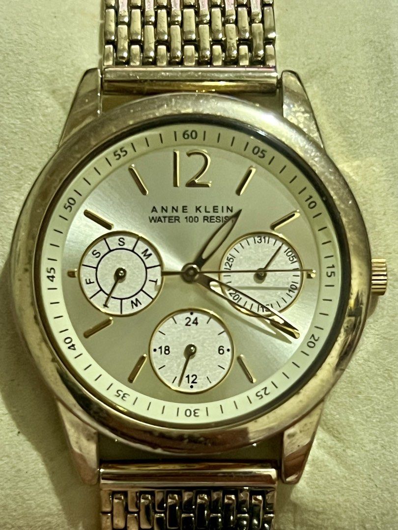 Anne Klein Gold Multifunction Watch (Category: Women's Watches) located in Dagupan City. Submitted by casadebayongph (Listing ID 1468327271, Image 2). Description: - Brand: Anne Klein - Color/Finish: Gold-tone with a polished bezel and case - Dial: Round champagne sunburst dial with day, date, and 24-hour sub-dials - Markers: Number 12 at the top with baton hour indicators - Band: Textured link bracelet with deployment clasp - Movement & Water Re