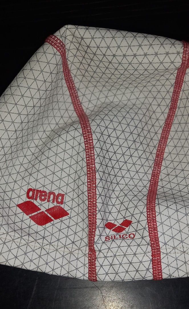 Arena Silico Swim Cap White Red Geometric (Category: Bikinis & Swimsuits) located in Cagayan de Oro. Submitted by edwardryan01984 (Listing ID 1468323459, Image 2). Description: - Brand: Arena - Material: Durable silicone for training and lap swimming - Design: Geometric triangle pattern in white and dark grey with red center stitching - Logos: Red Arena logo on the side and Silico branding near the base - Size: Standard adult sizing.