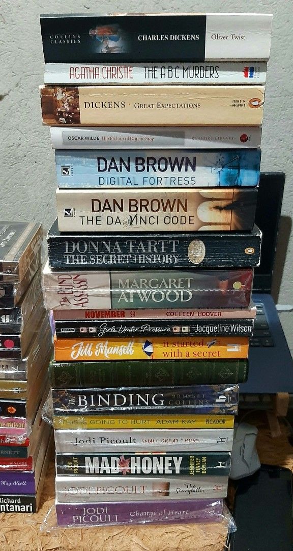 Assorted Fiction and Classic Novels Book Bundle (Category: Storybooks) located in Manila. Submitted by ayireads (Listing ID 1468395305, Image 3). Description: - Massive stack of fiction novels and classic literature - Authors include Charles Dickens, Dan Brown, Jodi Picoult, Jacqueline Wilson, Jane Austen, and Khaled Hosseini - Mostly paperback editions - Many books are still wrapped in plastic protection - Genres include thrillers, romance, cont