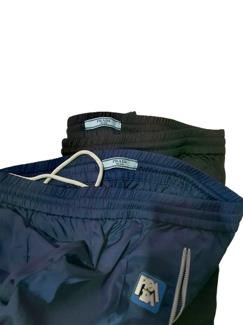 Authentic 💯 2pcs Prada Nylon Jogging Pants Track Pants (Category: Luxury Apparel) located in Tagum. Submitted by maryjanepradalux (Listing ID 1468320273, Image 2). Description: - Brand: Prada (with Milano inner tags) - Material: Premium nylon - Colors Available: Navy Blue and Black - Fit: Relaxed fit for casual wear and streetwear - Features: Elastic waistband with adjustable drawstring, secure zippered front pockets, and iconic rubber logo patc