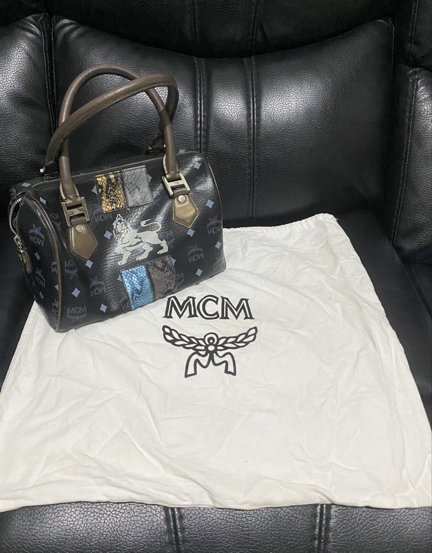 Authentic MCM Monogram Boston Handbag with Dust Bag (Category: Luxury Bags & Wallets) located in Manila. Submitted by switchcity (Listing ID 1468431379, Image 1). Description: - Authentic black MCM Boston handbag with signature monogram print - Features a bold lion graphic and unique exotic skin-textured patches on the front - Equipped with dual brown leather grab handles and a secure zip-top closure - Spacious interior designed to easily fit you