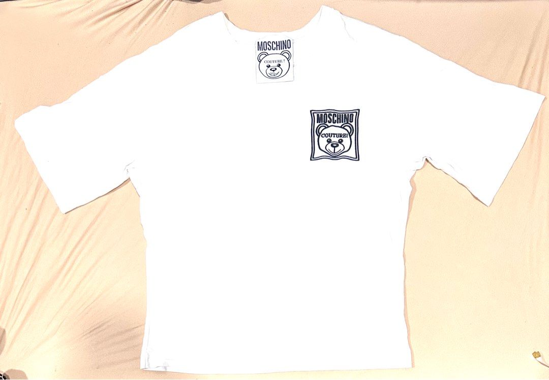 Authentic Moschino Couture Teddy Bear Patch Oversized T-Shirt (White) (Category: Shirts) located in Antipolo. Submitted by shopaho_nique (Listing ID 1468287991, Image 2). Description: 100% AUTHENTIC MOSCHINO COUTURE! Authenticity guaranteed with official AEFFE S.p.a. production tags inside (Product Code: 191D1A07791040). Not replica, not premium copy. Money back if proven fake. Very cute iconic Moschino Teddy Bear patch on the front. Premium heav