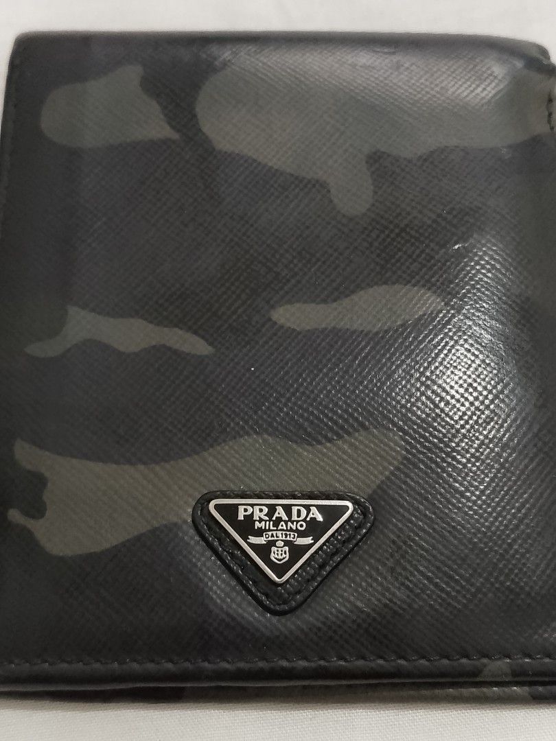 Authentic Prada Saffiano Camouflage Bifold Wallet (Category: Luxury Bags & Wallets) located in Manila. Submitted by anvicnicajeff (Listing ID 1468457979, Image 1). Description: - Brand: Prada -Authentic - Style: Bifold wallet - Material: Saffiano leather with black camouflage pattern - Hardware: Iconic silver-tone metal triangle logo - Interior: Multiple card slots and bill compartment with 'Made in Italy' tag - Condition: Shows normal wear aroun