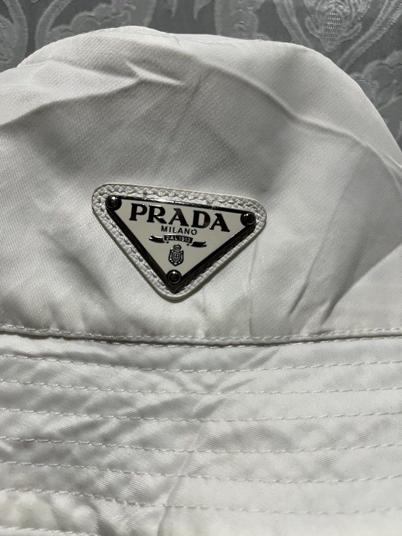 Authentic Prada White Re-Nylon Bucket Hat (Category: Hats & Beanies) located in General Santos City (Dadiangas). Submitted by thiftnibadi3 (Listing ID 1468420814, Image 2). Description: - Brand: Prada - Item: Bucket Hat - Color: Clean White - Size: M (tag inside) - Material: Polyester and cotton blend - Details: Iconic enameled metal triangle logo - Care: Dry clean only - Condition: Ready to wear, classic streetwear essential.
