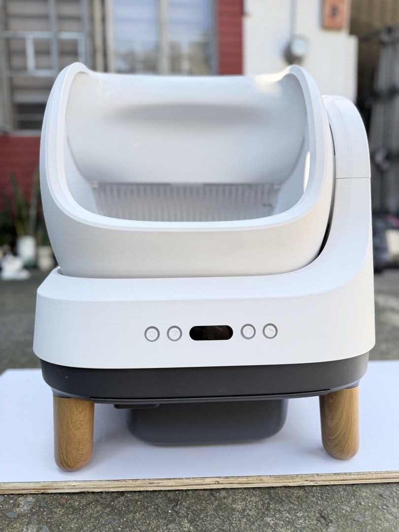 Automatic Smart Cat Litter Box Self-Cleaning (Category: Health & Grooming) located in Quezon City. Submitted by onlynina222 (Listing ID 1468341144, Image 2). Description: - Color: Clean white with stylish wooden legs - Design: Modern minimal look with a front control panel and easy-to-use power buttons - Interior: Gray inner lining with clear MIN and MAX fill level markers - Functionality: Built-in sifter grill for automatic waste management - Pe