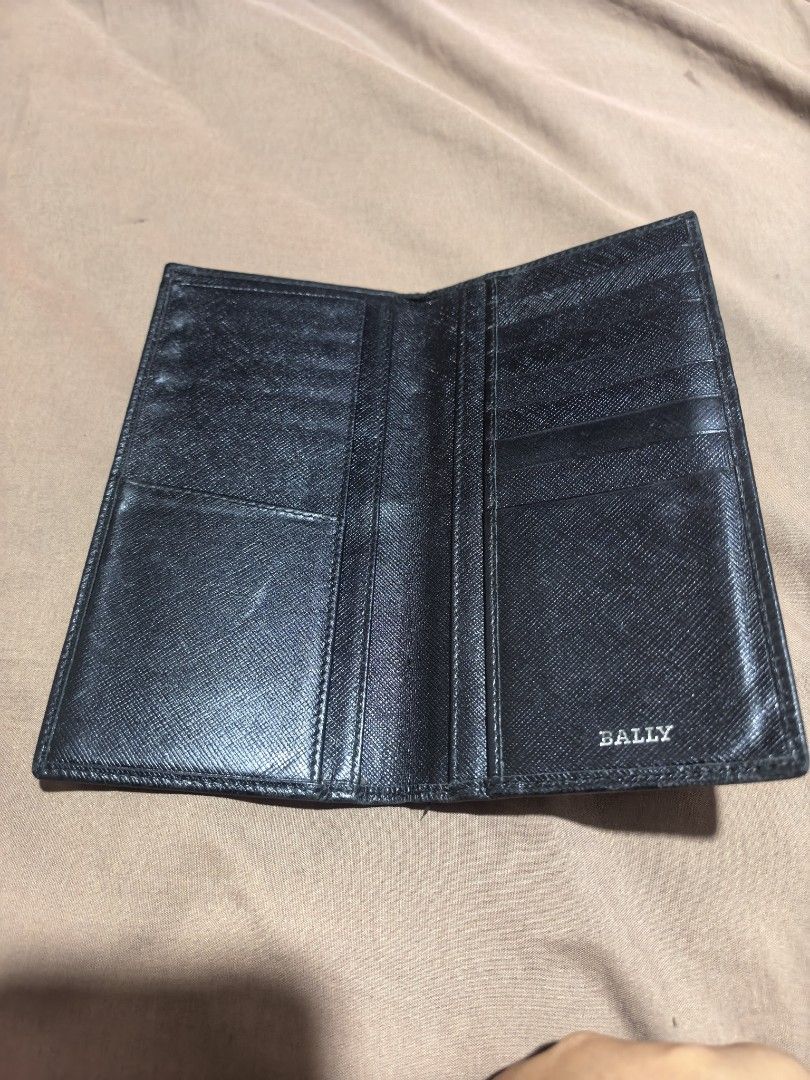 Bally Black Leather Long Wallet (Category: Luxury Bags & Wallets) located in Manila. Submitted by cura.ta88 (Listing ID 1468397863, Image 2). Description: - Brand: Bally - Material: Black saffiano leather - Hardware: Silver-tone metal 'B' logo on front - Features: Multiple card slots, slip pockets, and a spacious bill compartment - Condition: Exterior has normal signs of wear and surface scuffs near the top edge; interior is clean and all pockets