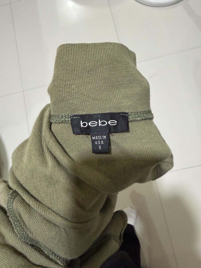 Bebe Olive Green Ribbed Zip-Up Jacket (Category: Coats, Jackets and Outerwear) located in Davao. Submitted by arbeepogio63169 (Listing ID 1468328236, Image 2). Description: - Brand: Bebe - Size: S (Made in U.S.A.) - Color: Olive green - Style: Fitted ribbed zip-up jacket with mock neck - Details: Signature rhinestone logo on left chest, branded metal zipper pull, and two front waist pockets - Condition: Excellent/Ready to wear.