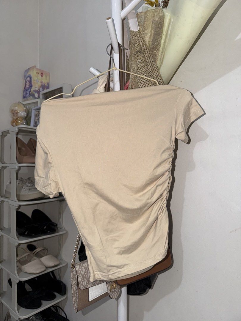 Beige Off-Shoulder Ruched Short Sleeve Top (Category: Blouses) located in Taguig. Submitted by deguzmanke83356 (Listing ID 1468330524, Image 2). Description: - Color: Beige - Style: Asymmetrical off-shoulder neckline with short sleeves - Fit: Fitted with flattering side ruched detailing - Material: Stretchy, super comfortable fabric - Easy to pair with high-waisted jeans or skirts.