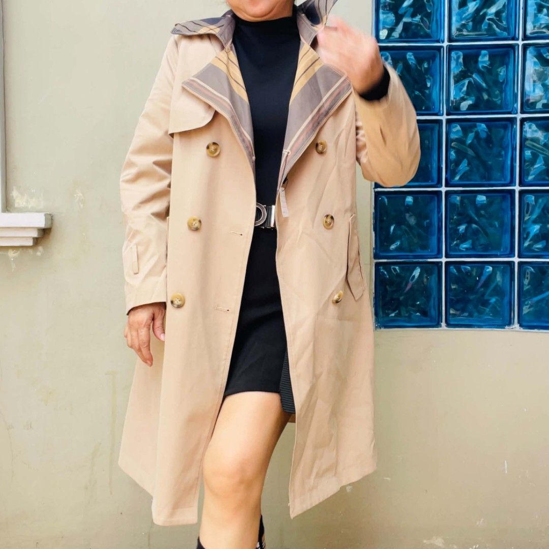 Beige Trench Coat with Plaid Collar Detail (Category: Coats, Jackets and Outerwear) located in Bulacan. Submitted by fenph2021 (Listing ID 1468303582, Image 1). Description: - Color: Classic beige - Style: Double-breasted mid-length trench coat (hits above the knee) - Details: Brown tortoise-style buttons on front and cuffs, hidden plaid or striped pattern under the lapels - Fit: Structured and clean fabric - Season: Great layering piece for cool