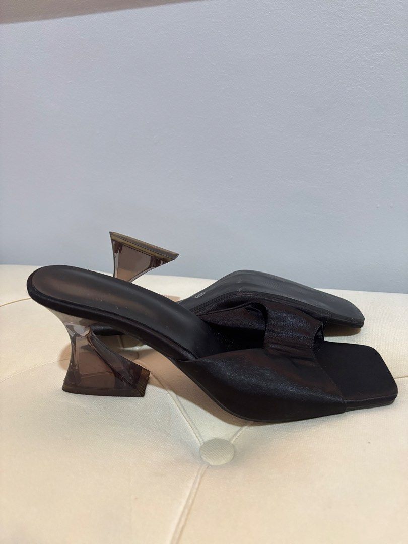 Black Heeled Mules with Clear Unique Heel Size 43 (Category: Heels) located in Quezon City. Submitted by hadescloset (Listing ID 1468394763, Image 1). Description: - Style: Black mules with open square toes and wide strap - Heel: Unique translucent brownish sculptured heel - Material: Smooth fabric upper - Size: 43 - Condition: Minor scuffs on the sole from wearing outside, overall good pre-loved condition.