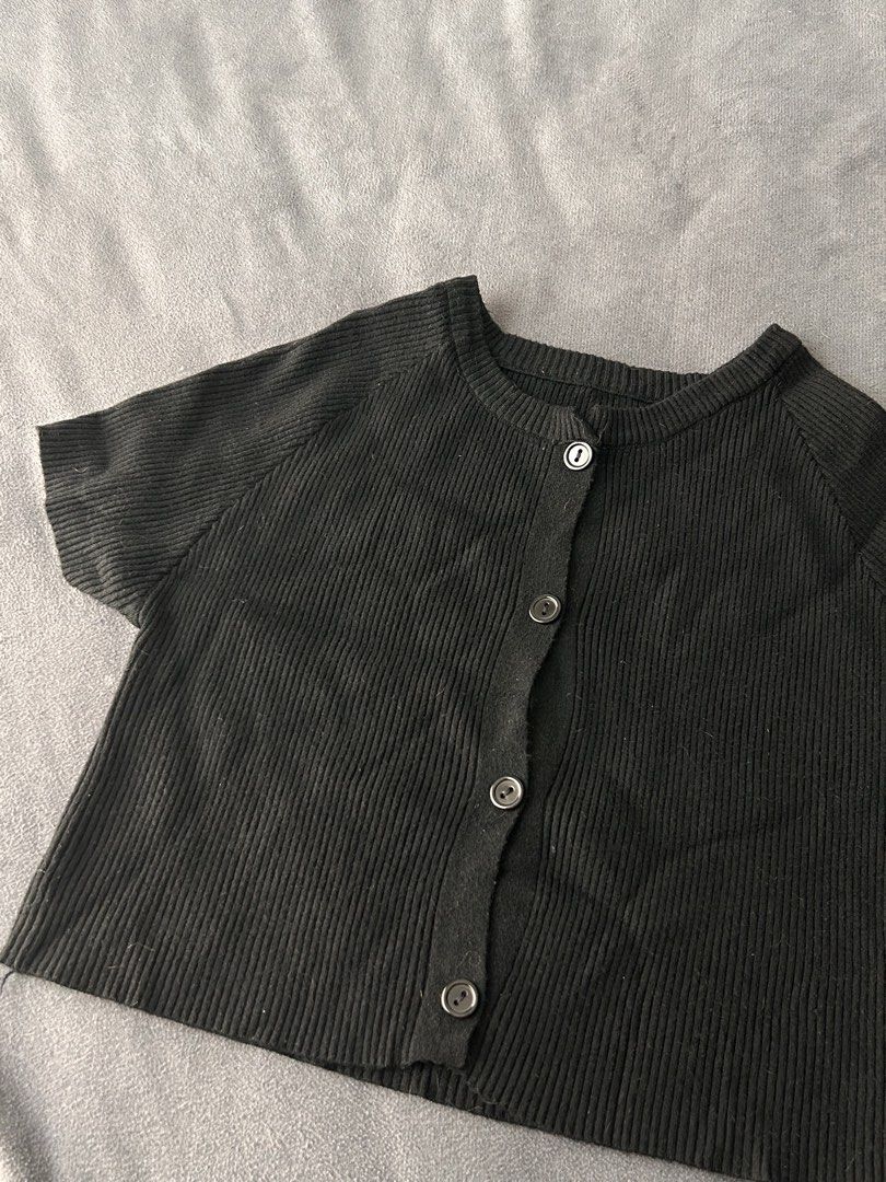 Black ribbed short sleeve button up crop top (Category: Blouses) located in Pasig City. Submitted by cha.declutterz (Listing ID 1468334972, Image 2). Description: - Color: Black - Free size (S-M) - Style: Short-sleeve ribbed cardigan top with front buttons - Fit: Cropped length, round neckline - Material: Soft and stretchy knit - Pairing: Great for matching with high-waisted pants or skirts.