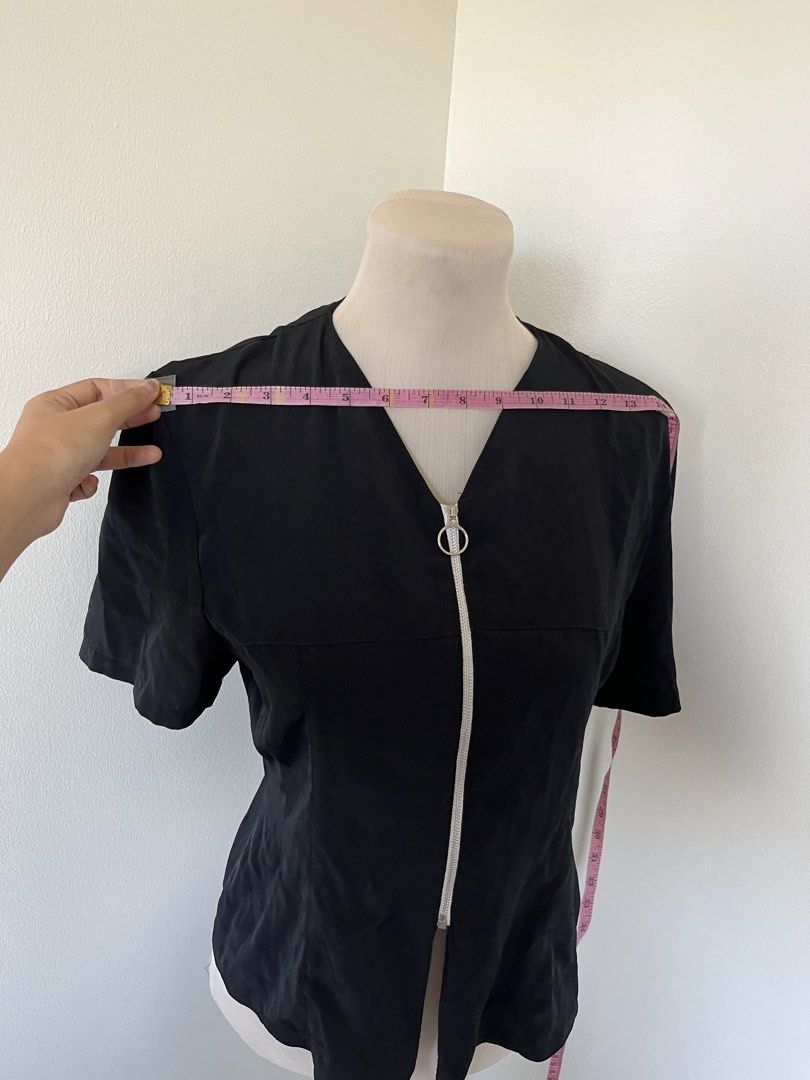 Black short-sleeve top with silver ring zipper (Category: Blouses) located in Mandaluyong City. Submitted by bravedeer.020ad7 (Listing ID 1468364820, Image 2). Description: - Color: Black - Style: Short-sleeve blouse with V-neck and front zipper - Accent: Trendy silver ring pull - Fit: Structured cut - Size/Measurements: Approx. 14 inches across the chest, 22 inches in length - Condition: Clean fabric, excellent overall condition.