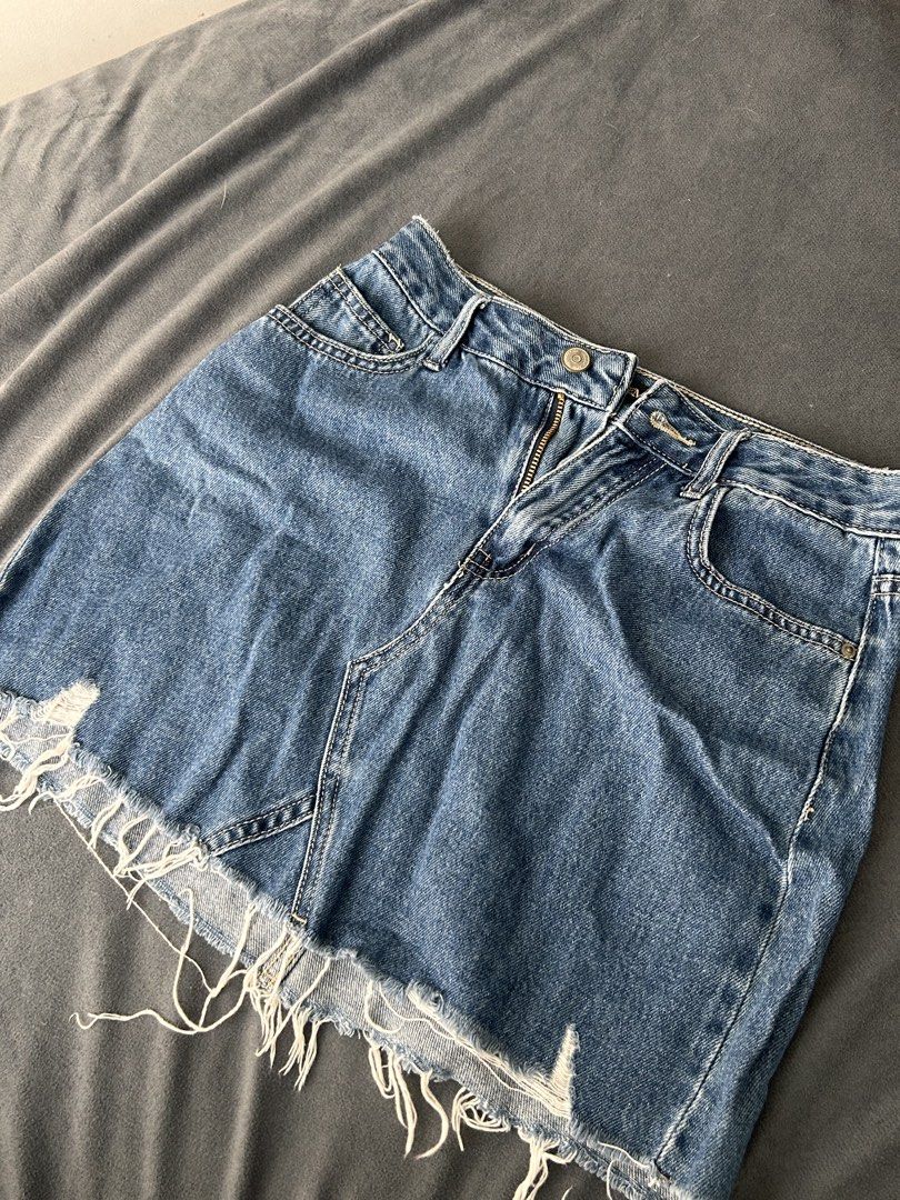 Blue Denim Mini Skirt Tattered (Category: Skirts) located in Pasig City. Submitted by cha.declutterz (Listing ID 1468336059, Image 2). Description: - Brand: Semir - Size: Medium (Fits 26-27) - Color: Medium blue wash - Details: Raw frayed hem, front distressing, brass-tone zip fly with button closure - Pockets: Classic five-pocket styling with belt loops - Condition/Material: Sturdy denim fabric, perfect for everyday casual wear.