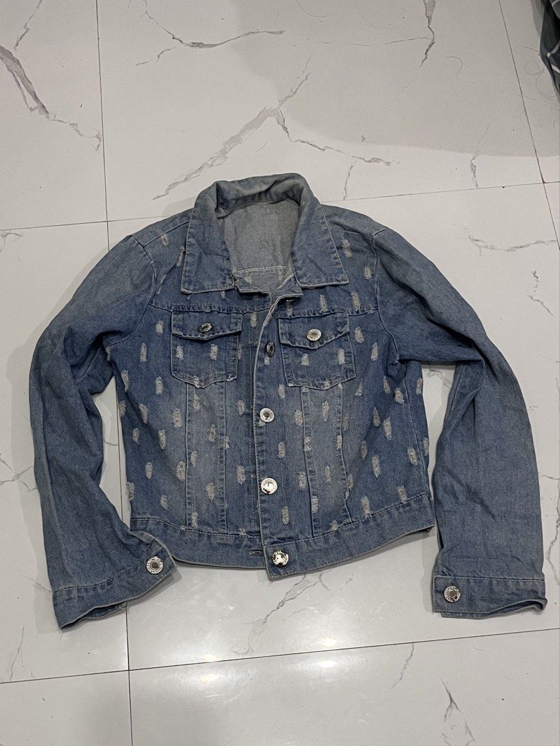 Blue Distressed Denim Jacket with Front Pockets (Category: Coats, Jackets and Outerwear) located in Mabalacat. Submitted by xyzamym (Listing ID 1468407088, Image 1). Description: - Classic blue denim jacket -Small to Medium - Heavy distressing throughout front and sleeves - Two button-flap chest pockets - Metal button closures and button cuffs - Great layering piece for casual outfits - Fits true to size.
