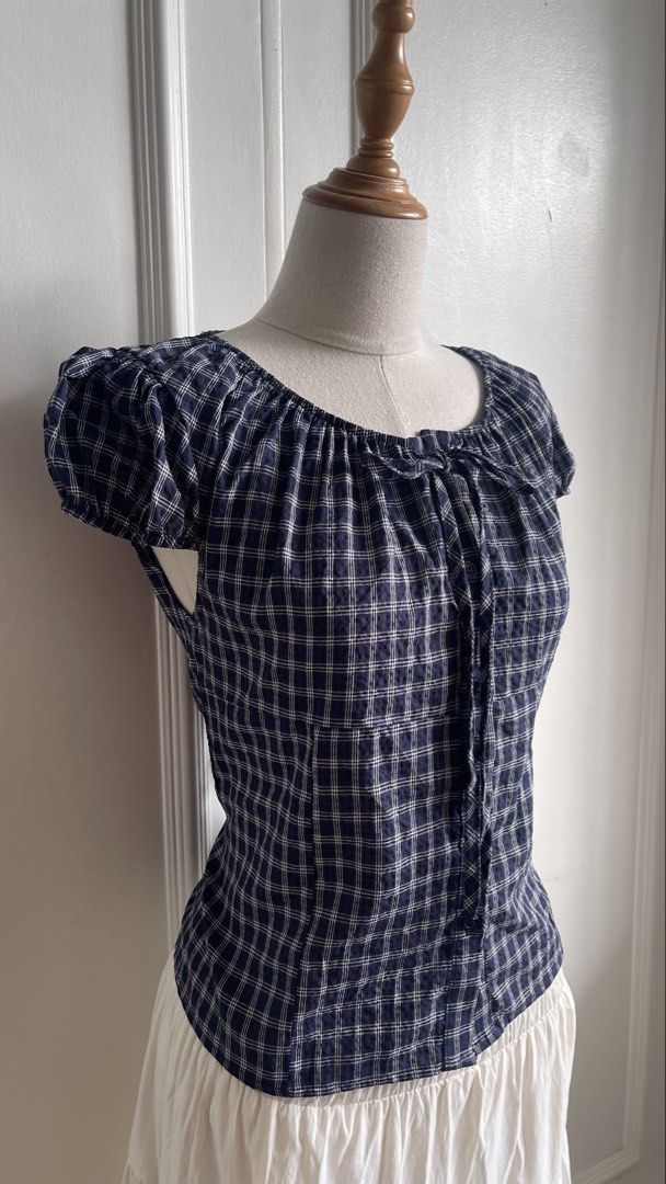 Blue Plaid Short Sleeve Tie-Front Blouse (Category: Blouses) located in Cavite. Submitted by devilourea (Listing ID 1468302596, Image 2). Description: - Classic navy blue and white plaid pattern - Trendy square neckline with cute front tie detail - Short puff sleeves and functional center button-down - Flattering slim fit that hits right at the waist - Pairs effortlessly with high-waisted jeans or skirts - Condition: Brand new / Excellent - Mode 
