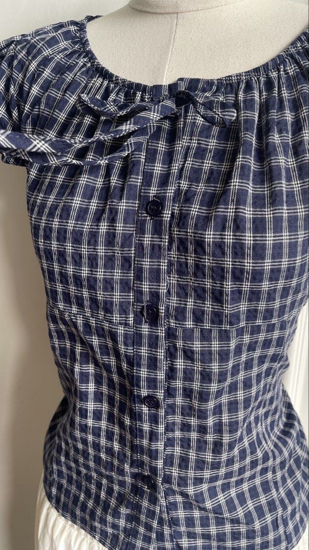 Blue Plaid Short Sleeve Tie-Front Blouse (Category: Blouses) located in Cavite. Submitted by devilourea (Listing ID 1468302596, Image 3). Description: - Classic navy blue and white plaid pattern - Trendy square neckline with cute front tie detail - Short puff sleeves and functional center button-down - Flattering slim fit that hits right at the waist - Pairs effortlessly with high-waisted jeans or skirts - Condition: Brand new / Excellent - Mode 