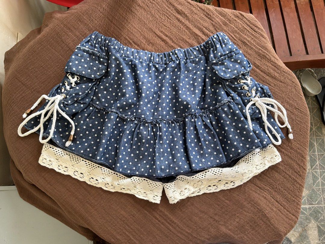 Blue Polka Dot Skort with Lace Trim (Category: Skirts) located in Dumaguete. Submitted by _l1lyy_ (Listing ID 1468343965, Image 1). Description: - Fit: M-L - Blue denim-style skort with adorable white polka dots - Layered ruffle design finished with charming beige crochet lace trim - Adjustable side lacing with thick white ropes and metallic grommets - Comfortable elastic waistband for an easy and flexible fit - Cute, playful piece perfect for ca