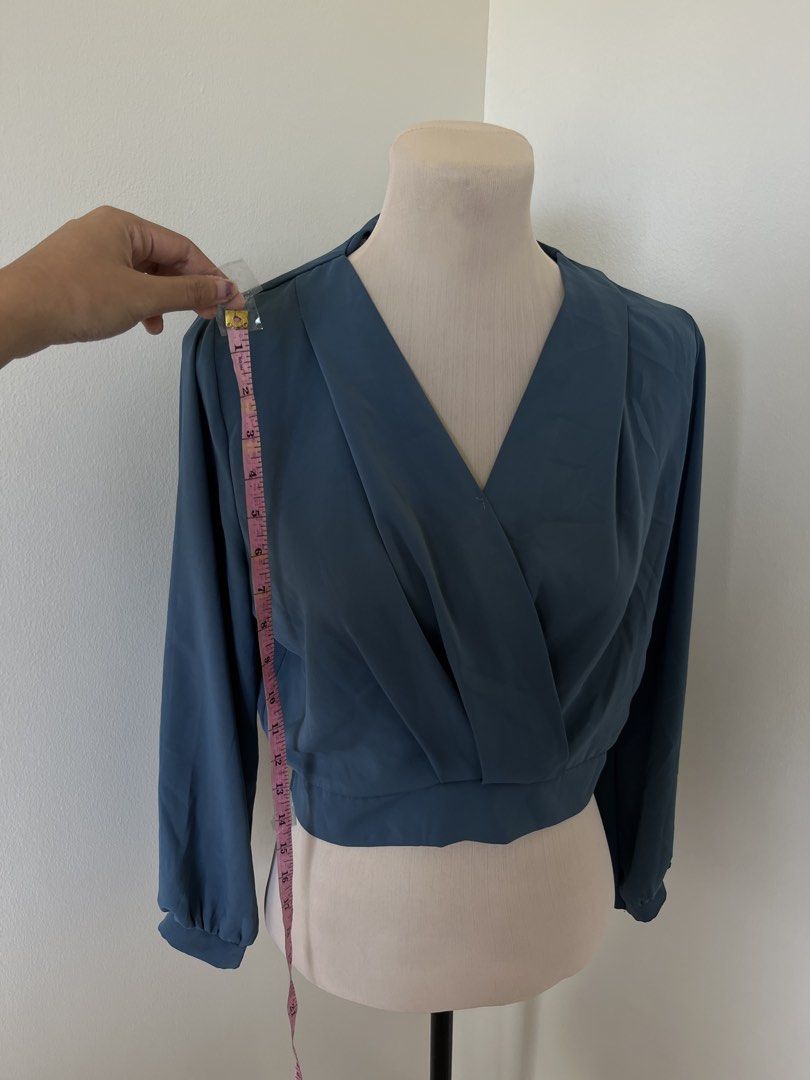 Blue Wrap Crop Blouse Long Sleeves (Category: Longsleeves) located in Mandaluyong City. Submitted by bravedeer.020ad7 (Listing ID 1468362731, Image 3). Description: - Color: Solid Blue - Style: Wrap crop blouse with long sleeves - Features: Pleated neckline and fitted, clean-cut waistband - Fabric: Smooth and lightweight - Measurements: ~14 inches across the chest, ~17 inches from shoulder to hem - Condition: Excellent.