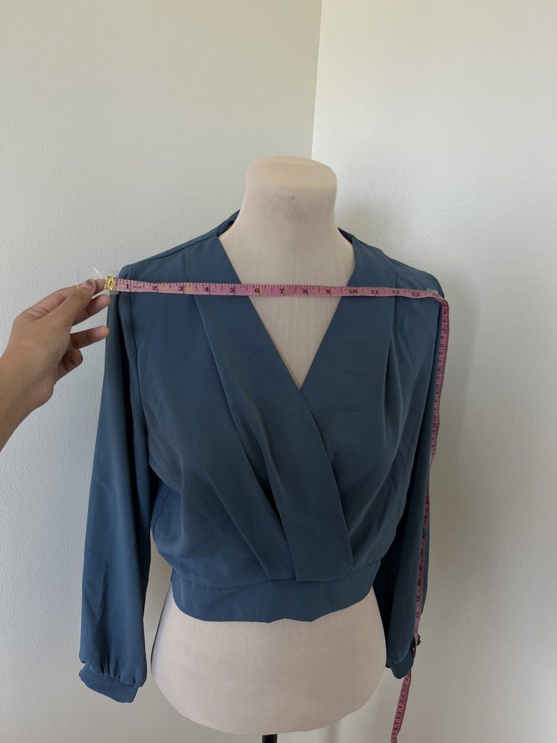 Blue Wrap Crop Blouse Long Sleeves (Category: Longsleeves) located in Mandaluyong City. Submitted by bravedeer.020ad7 (Listing ID 1468362731, Image 2). Description: - Color: Solid Blue - Style: Wrap crop blouse with long sleeves - Features: Pleated neckline and fitted, clean-cut waistband - Fabric: Smooth and lightweight - Measurements: ~14 inches across the chest, ~17 inches from shoulder to hem - Condition: Excellent.